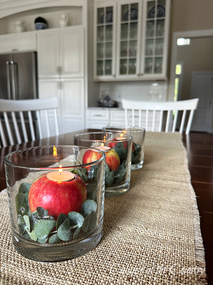 DIY apple candle holders in glass hurricane vases on table