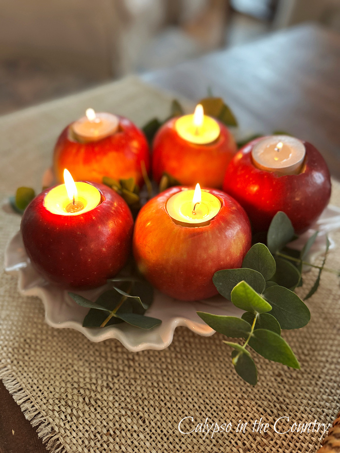 Five apples with tea lights on white leaf plate with eucalyptus - DIY apple candle holders