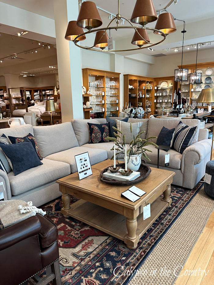 Sectional sofa with navy blue pillows and navy and red rug in store display - September wrap up