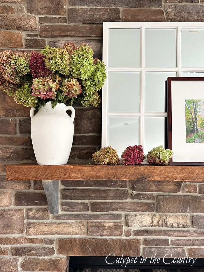 Stone fireplace with white window pane mirror and white vase filled with hydrangeas on mantel - September wrap up